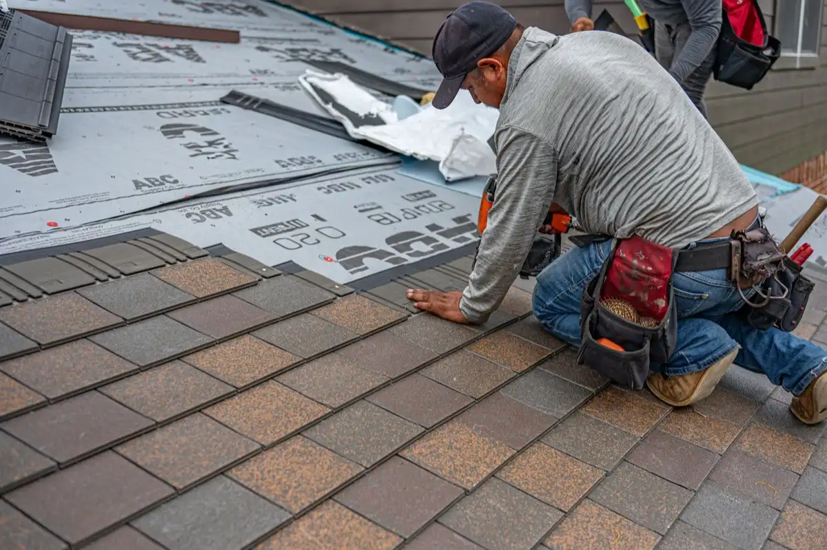 Roofer nailing the cap course along a ridge on a home in Toms River, NJ